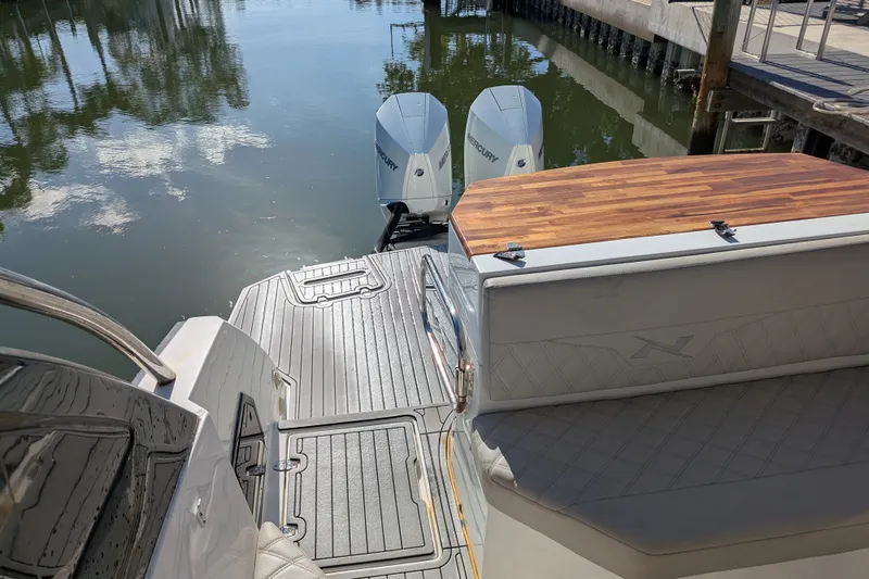 Slide: The Image of 2023 NX Boats 340 Sport Coupe with dual Mercury engines, docked on calm water. - 43