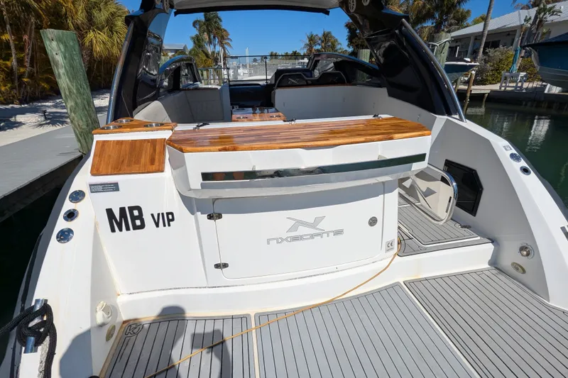 Slide: The Image of 2023 NX Boats 340 Sport Coupe at dock, featuring sleek design and wooden accents. - 42