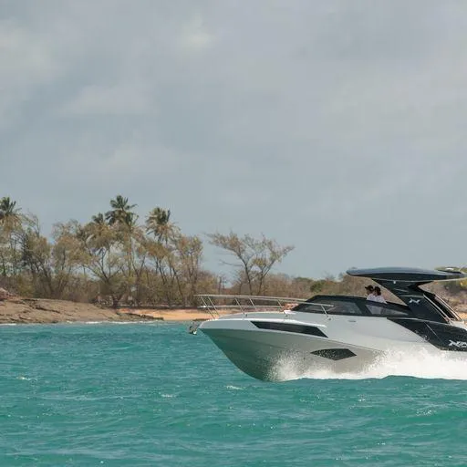 Slide: The Image of Manufacturer Provided Image: 2023 NX Boats 340 Sport Coupe cruising on turquoise waters near a tropical shoreline. - 14