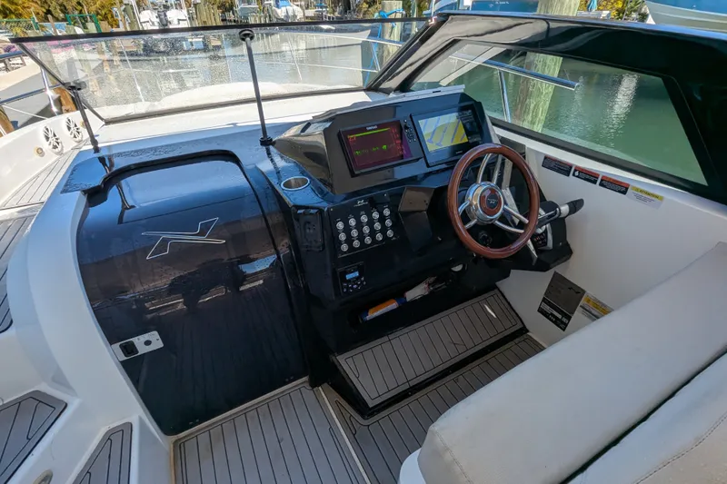 Slide: The Image of 2023 NX Boats 340 Sport Coupe helm with modern controls and wooden steering wheel. - 15