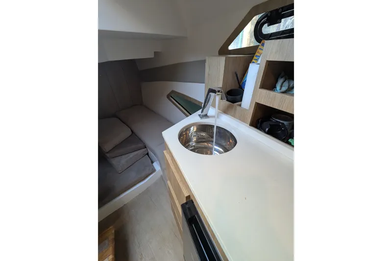 Slide: The Image of Interior of 2023 NX Boats 340 Sport Coupe with modern kitchenette and cozy seating area. - 22