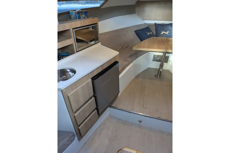 Slide: The Image of 2023 NX Boats 340 Sport Coupe interior with kitchenette and seating area. - 28