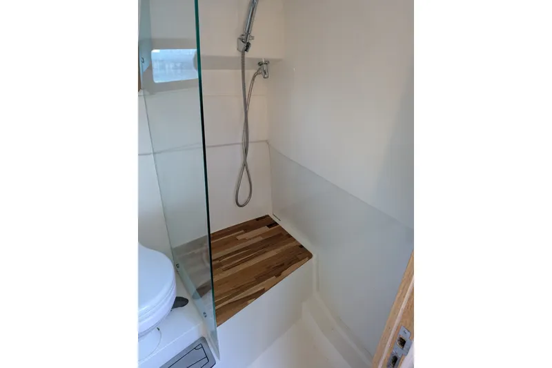 Slide: The Image of Modern shower area in 2023 NX Boats 340 Sport Coupe with wooden bench and glass partition. - 35