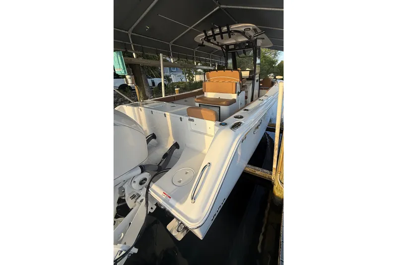 Slide: The Image of 2025 Sea Hunt Gamefish 27FS boat docked under a canopy, showcasing sleek design and seating. - 15