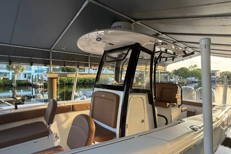 Slide: The Image of 2025 Sea Hunt Gamefish 27FS boat docked under canopy, featuring sleek design and comfortable seating. - 28