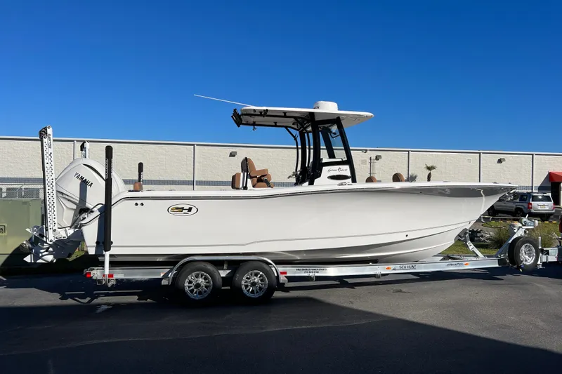 Slide: The Image of 2025 Sea Hunt Gamefish 27FS boat on trailer, side view, clear blue sky background. - 1