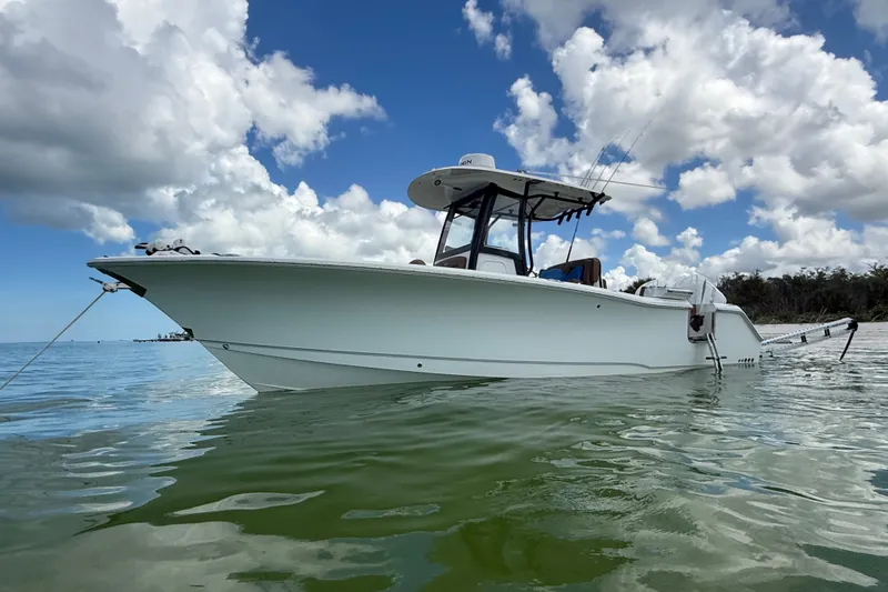 Slide: The Image of 2025 Sea Hunt Gamefish 27FS boat anchored in calm waters under a partly cloudy sky. - 5