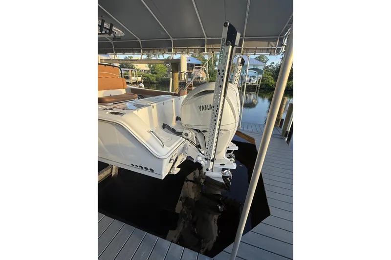 Slide: The Image of 2025 Sea Hunt Gamefish 27FS boat with Yamaha engine, docked under a canopy. - 10