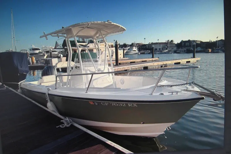 Slide: The Image of 2016 Edgewater 208CC boat docked at marina, clear sky, calm water. - 12