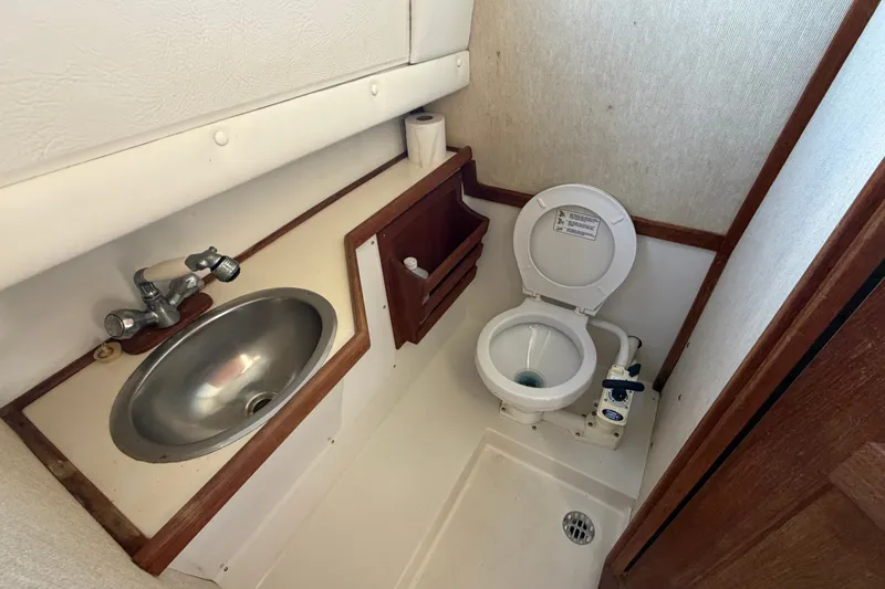 Slide: The Image of 1994 Skipjack 262 Flybridge boat bathroom with sink and marine toilet. - 27