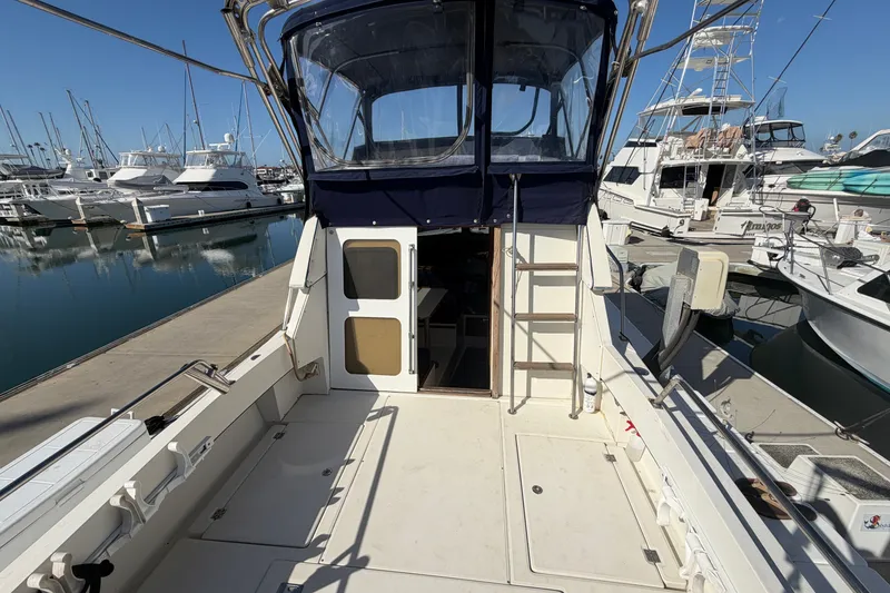 Slide: The Image of 1994 Skipjack 262 Flybridge boat docked at marina, featuring spacious deck and flybridge. - 13