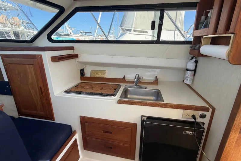 Slide: The Image of 1994 Skipjack 262 Flybridge boat interior with kitchenette, sink, stove, and storage cabinets. - 24