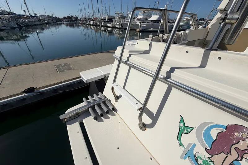 Slide: The Image of 1994 Skipjack 262 Flybridge boat docked at marina with mermaid decal. - 37