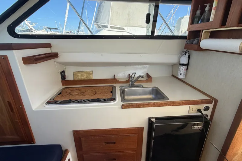 Slide: The Image of 1994 Skipjack 262 Flybridge boat interior with kitchenette, sink, stove, and storage. - 26