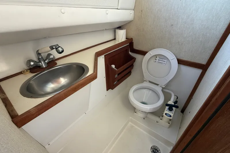 Slide: The Image of 1994 Skipjack 262 Flybridge boat bathroom with sink and marine toilet. - 29
