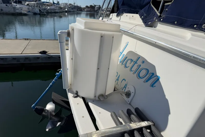 Slide: The Image of 1994 Skipjack 262 Flybridge boat docked, featuring a white storage unit and visible propeller. - 38