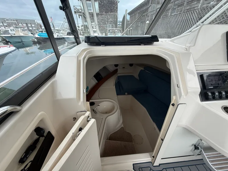Slide: The Image of Cabin of the Grady-White Gulfstream 232 with blue seating and helm console, docked at a marina. - 27
