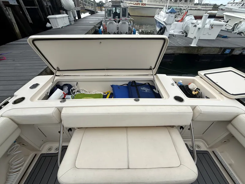 Slide: The Image of The image shows the storage area of a 2015 Grady-White Gulfstream 232 boat. The storage is open, containing various items like ropes and bags. The boat is docked, surrounded by other boats. - 16