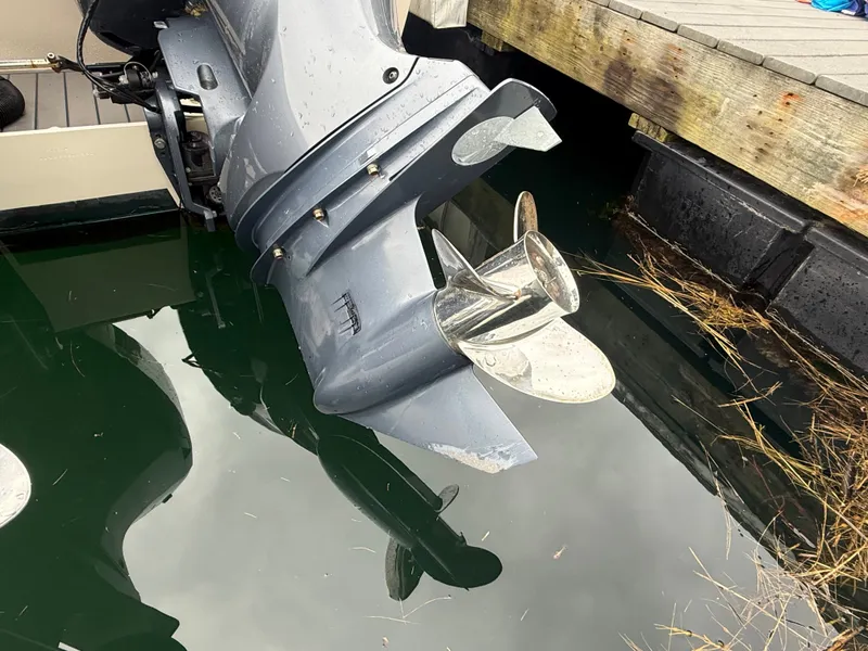 Slide: The Image of An outboard motor of a boat in the water next to a wooden dock. - 6