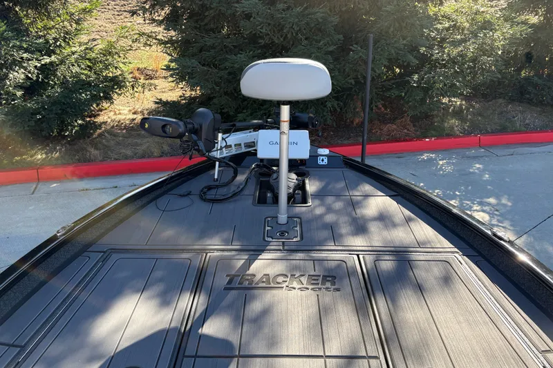 Slide: The Image of 2027 Tracker Savage 215 boat deck with Garmin equipment, surrounded by greenery. - 14