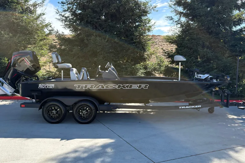 The Image of 2027 Tracker Savage 215 boat on trailer, parked outdoors with trees in background. - 0