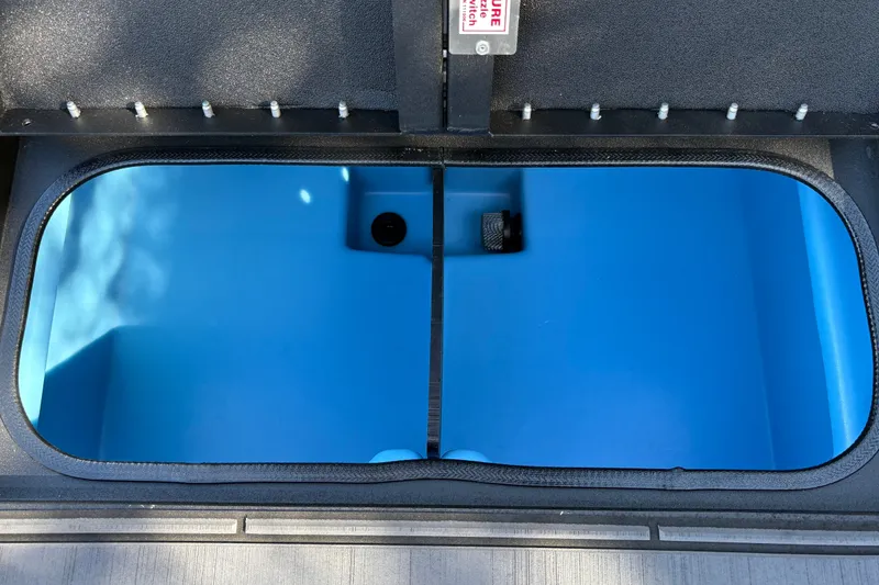 Slide: The Image of Open storage compartment in 2027 Tracker Savage 215 boat, featuring a blue interior. - 28