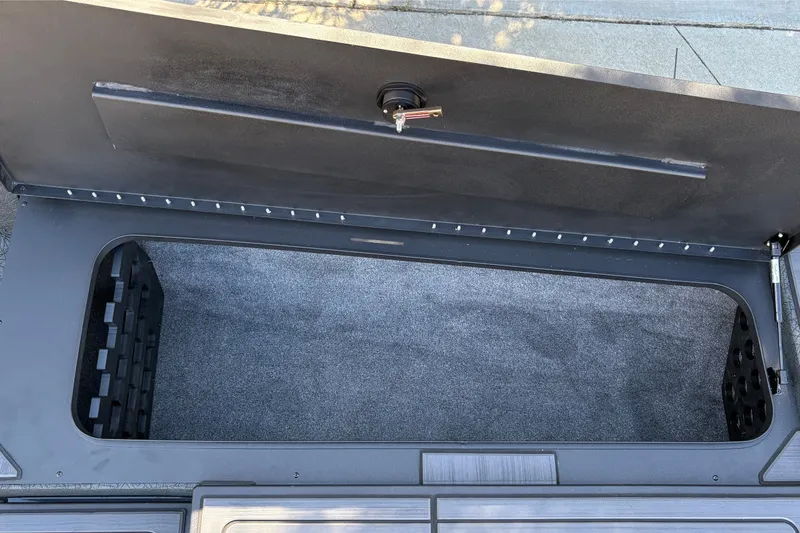 Slide: The Image of Open storage compartment of 2027 Tracker Savage 215 boat, featuring carpeted interior. - 36