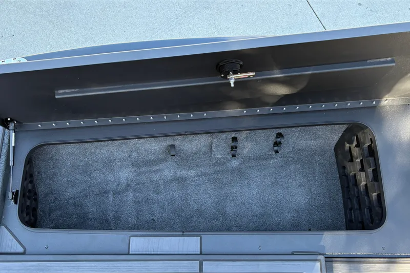 Slide: The Image of Storage compartment of 2027 Tracker Savage 215 boat, featuring carpeted interior and secure latch. - 29