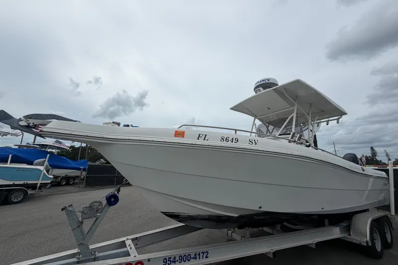 Slide: The Image of 2021 Key Largo 2650WI boat on trailer, overcast sky background. - 6