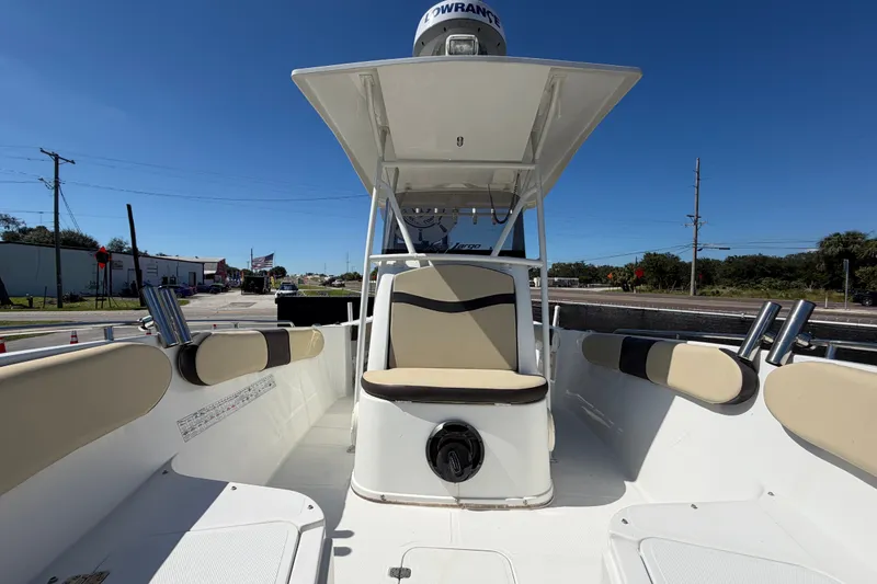 Slide: The Image of 2021 Key Largo 2650WI boat interior with seating and rod holders under clear blue sky. - 56