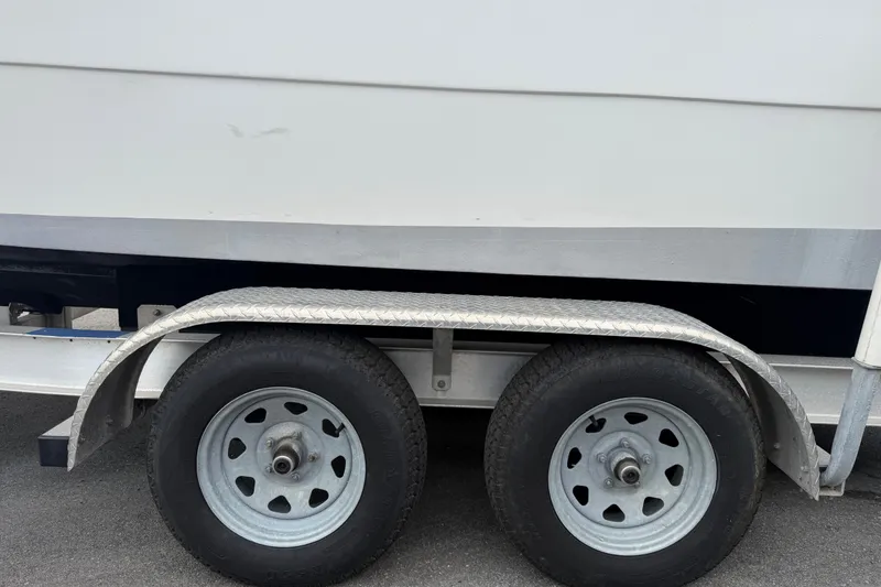 Slide: The Image of Trailer wheels of a 2021 Key Largo 2650WI boat on pavement. - 24