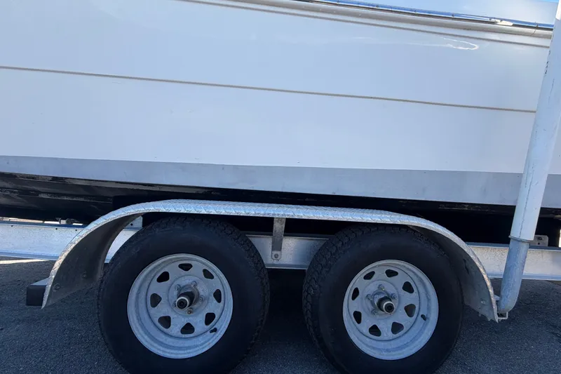 Slide: The Image of Trailer with Key Largo 2650WI boat, 2021 model, parked on asphalt surface. - 85