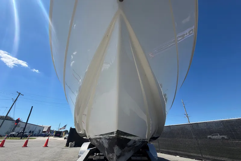 Slide: The Image of 2021 Key Largo 2650WI boat hull on trailer under clear blue sky. - 16