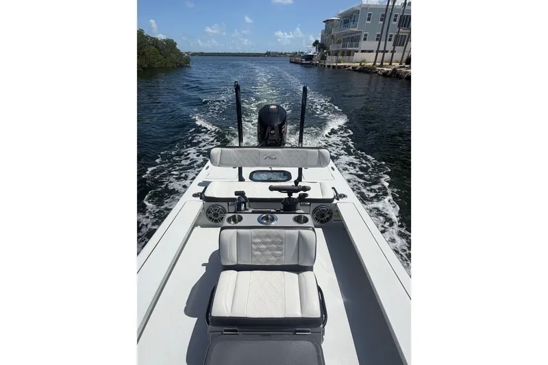 Slide: The Image of 2021 V-Tech 18 Flats boat cruising on a sunny waterway, surrounded by modern buildings. - 2
