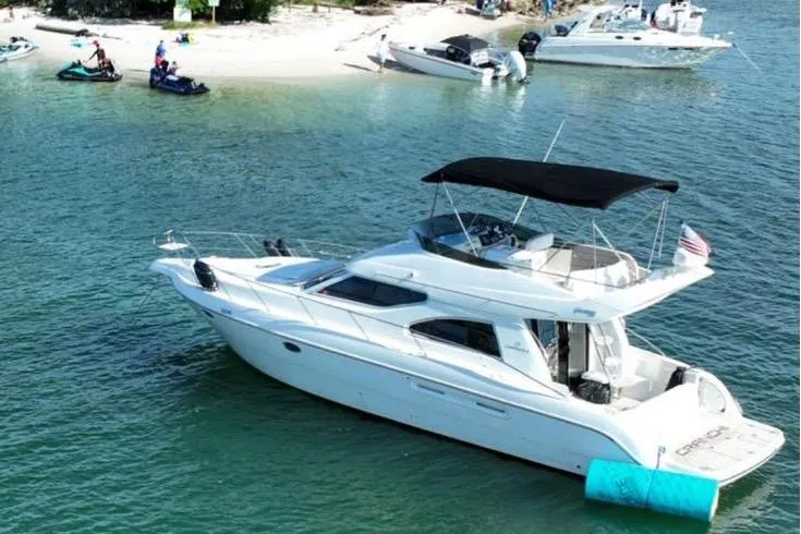 Slide: The Image of 2007 Cranchi Atlantique 40 yacht anchored near a sandy beach with jet skis and boats. - 1