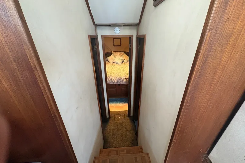 Slide: The Image of Interior hallway of a 1989 Topaz 44 Sportfisherman boat, leading to a cozy bedroom. - 23