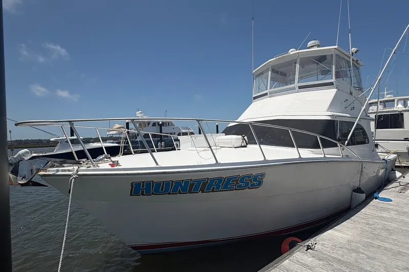 The Image of 1989 Topaz 44 Sportfisherman boat named "Huntress" docked at marina under clear sky. - 1