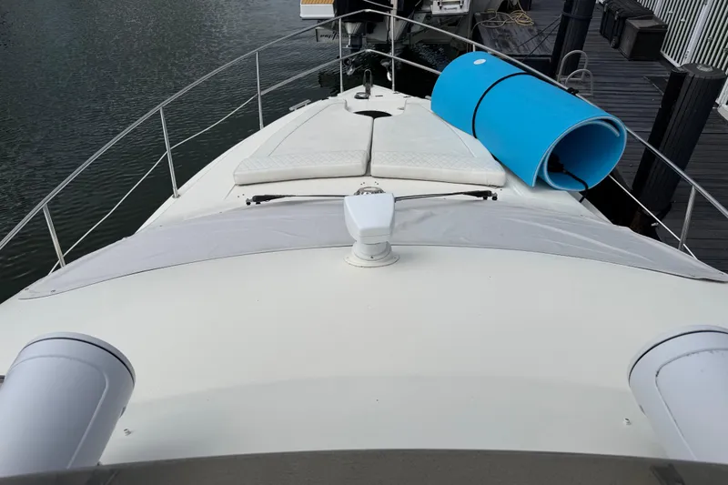 Slide: The Image of 2004 Azimut 39E yacht deck with sunbathing area and blue mat, docked by the water. - 6