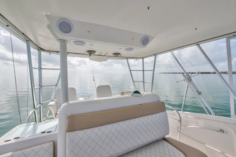 Slide: The Image of 2005 Luhrs 41 Convertible yacht interior with ocean view, featuring cushioned seating and fishing rods. - 25