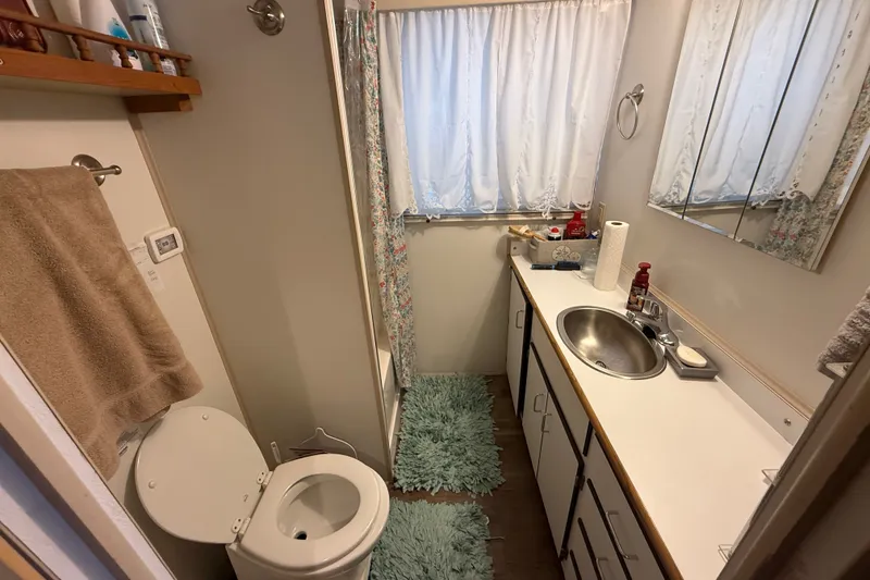 Slide: The Image of Compact bathroom in a 2003 Gibson 5500 SERIES, featuring sink, toilet, and storage cabinets. - 10