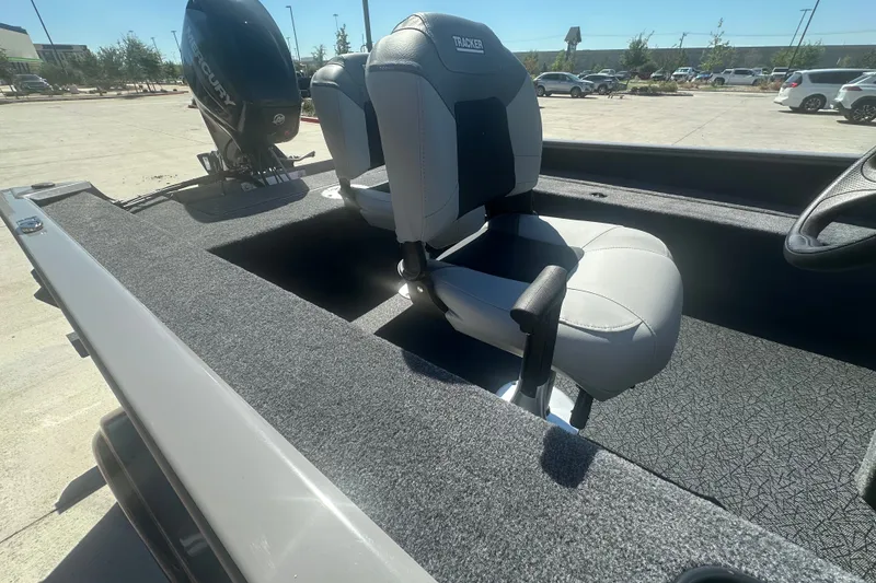 Slide: The Image of 2027 Tracker Super Guide V-16 SC boat interior with seating and motor, parked outdoors. - 16