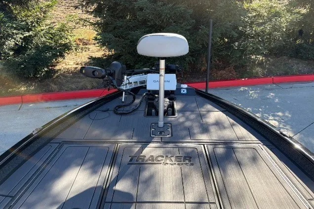 Slide: The Image of 2027 Tracker Savage 215 boat deck with Garmin equipment, surrounded by greenery. - 32