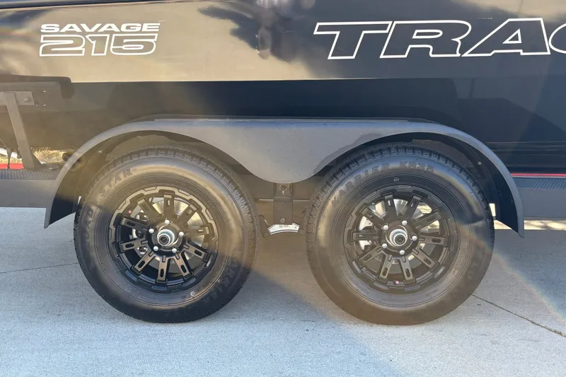 Slide: The Image of 2027 Tracker Savage 215 trailer with dual black wheels on concrete surface. - 40