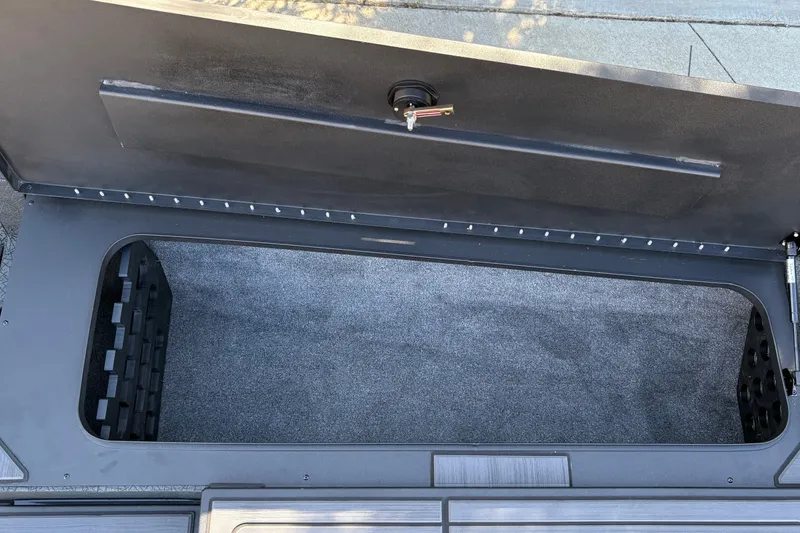 Slide: The Image of Open storage compartment of 2027 Tracker Savage 215 boat, featuring carpeted interior. - 38