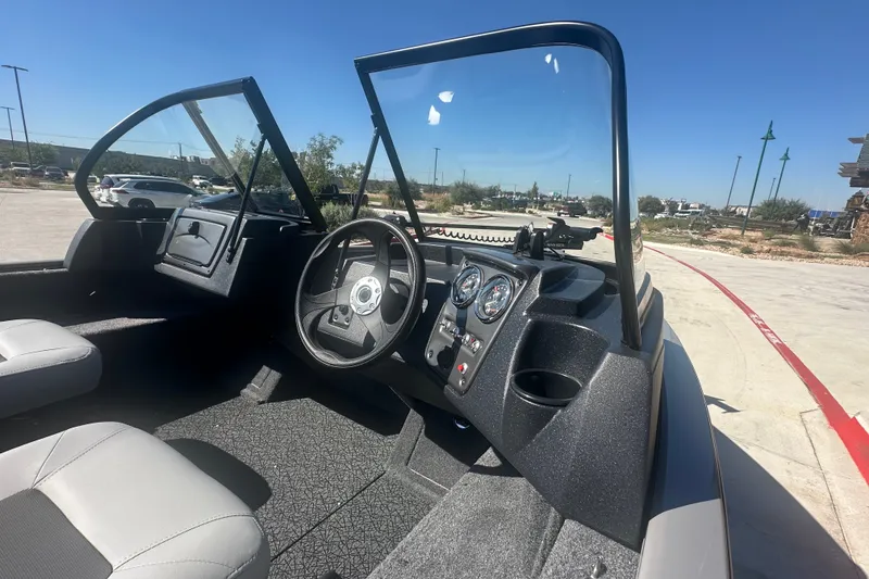 Slide: The Image of Interior view of 2027 Tracker Pro Guide V-16 WT boat, featuring steering wheel and dashboard. - 16