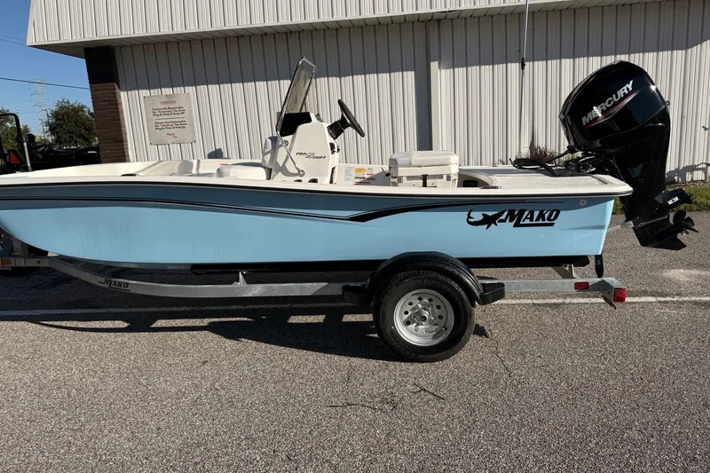 Slide: The Image of 2027 Mako Pro Skiff 15 CC boat on trailer, featuring a Mercury outboard motor. - 2