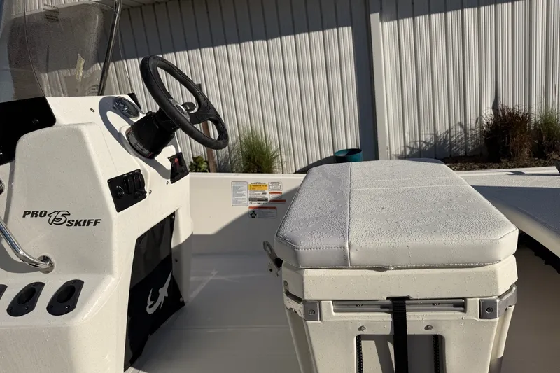 Slide: The Image of 2027 Mako Pro Skiff 15 CC boat interior with steering console and cushioned seat. - 8