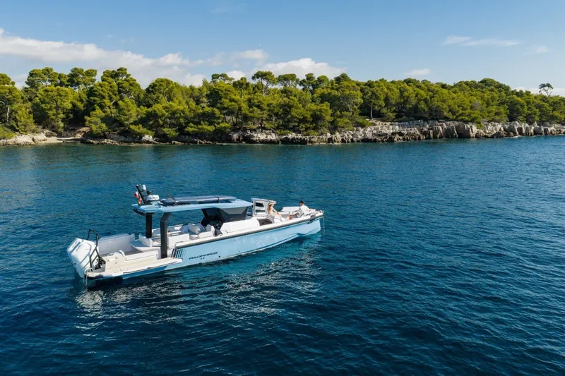 Slide: The Image of 2027 Axopar 38 Cross Top boat cruising near a lush, forested coastline. - 3