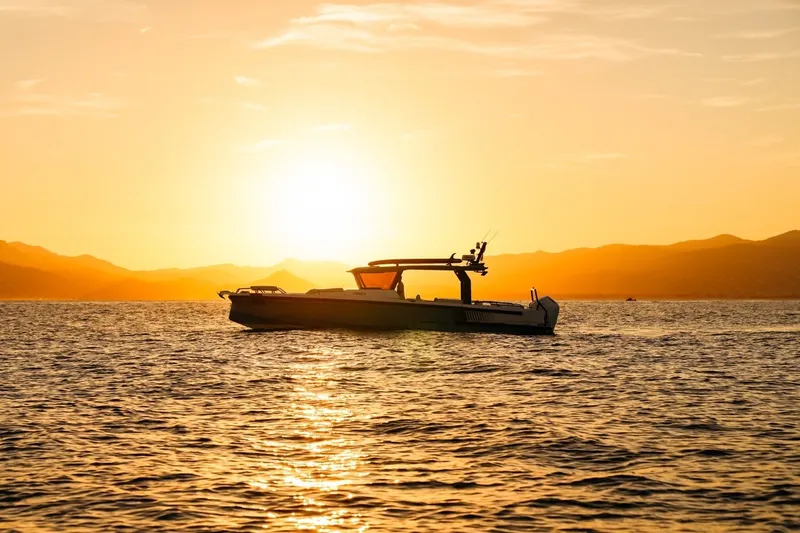 Slide: The Image of Axopar 38 Cross Top 2027 boat silhouetted against a stunning sunset over calm waters. - 12