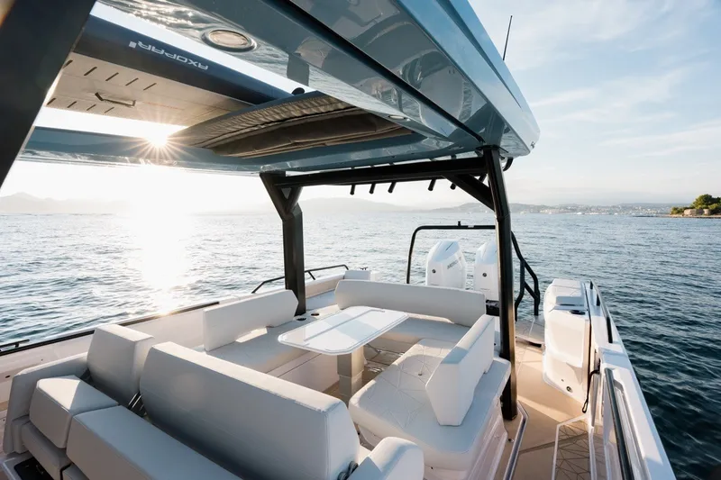 Slide: The Image of 2027 Axopar 38 Cross Top boat interior with seating, table, and ocean view. - 13